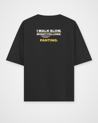 Black oversized tee, back view, print reading I walk slow. Money follows. Panting – digital mockup