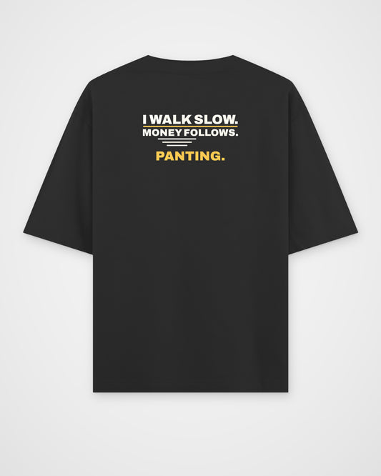 Black oversized tee, back view, print reading I walk slow. Money follows. Panting – digital mockup