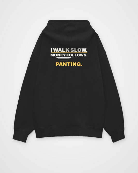 Black oversized hoodie, back view, print reading I walk slow. Money follows. Panting – digital mockup