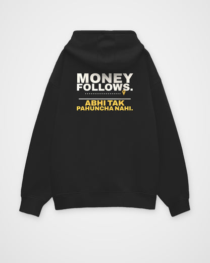 Black oversized hoodie, back view, print reading Money follows. Abhi tak pahuncha nahi – digital mockup