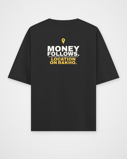Black oversized tee, back view, print reading Money follows. Location on rakho – digital mockup