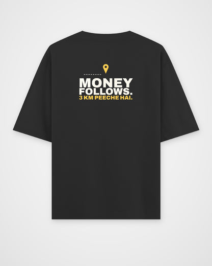 Black oversized tee, back view, print reading Money follows. 3 km peeche hai – digital mockup