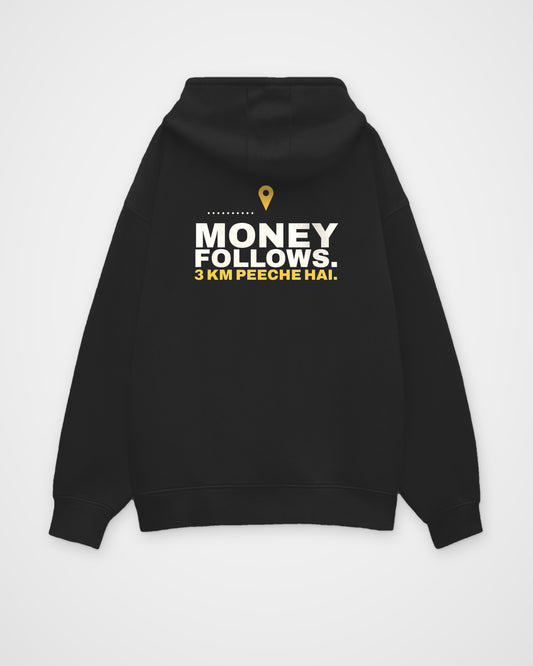 Black oversized hoodie, back view, print reading Money follows. 3 km peeche hai – digital mockup