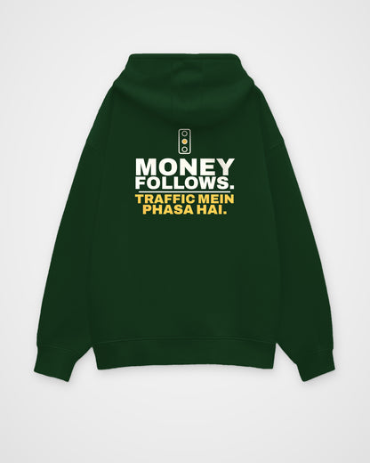 Bottle Green oversized hoodie, back view, print reading Money follows. Traffic mein phasa hai – digital mockup
