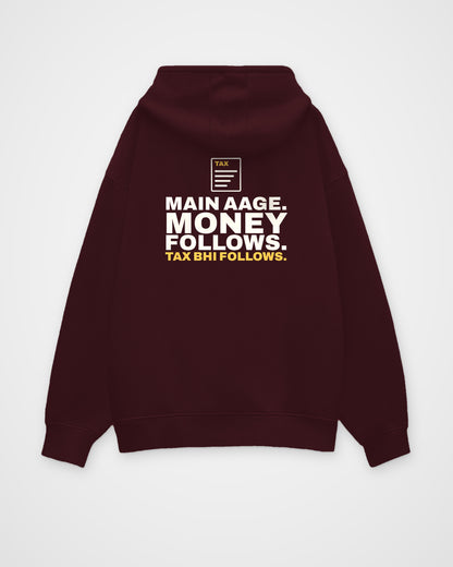 Maroon oversized hoodie, back view, print reading Main aage. Money follows. Tax bhi follows – digital mockup