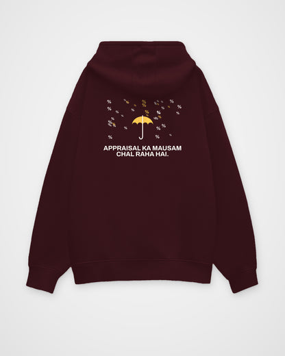 Maroon oversized hoodie, back view, with a small umbrella under a rain of percent signs and Appraisal ka – digital mockup