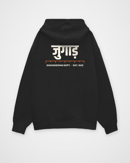 Black oversized hoodie, back view, a big Hindi wordmark reading jugaad, a ruler and ENGINEERING DEPT. EST – digital mockup
