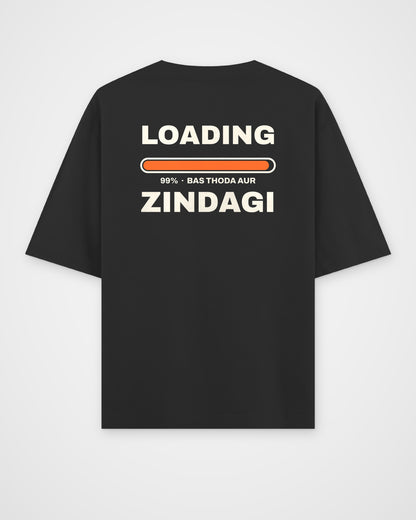 Black oversized t-shirt, back view, huge stacked LOADING 99% type with an orange progress bar stuck at 99% – digital mockup