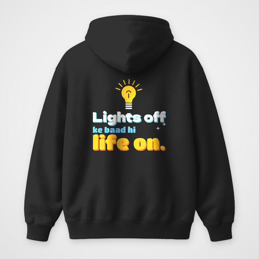 Black oversized hoodie, back view, glowing yellow bulb print with the words Lights off ke baad hi life on