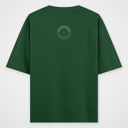 Bottle green oversized T-shirt, back view, small round seal reading KAM MAGAR POORA