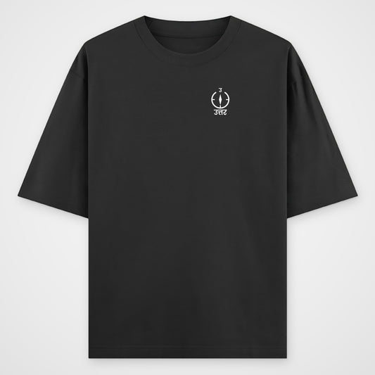 Black oversized T-shirt, front view, small white compass on the left chest with Devanagari text