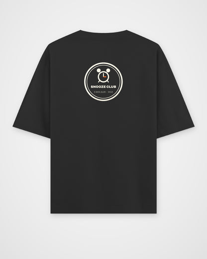 Black oversized t-shirt, back view, a round SNOOZE CLUB badge with an alarm clock and 5 MIN AUR ROZ – digital mockup