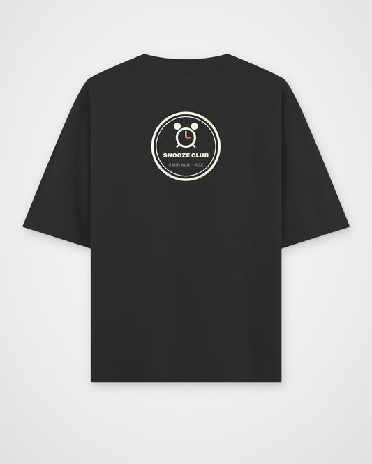 Black oversized t-shirt, back view, a round SNOOZE CLUB badge with an alarm clock and 5 MIN AUR ROZ – digital mockup