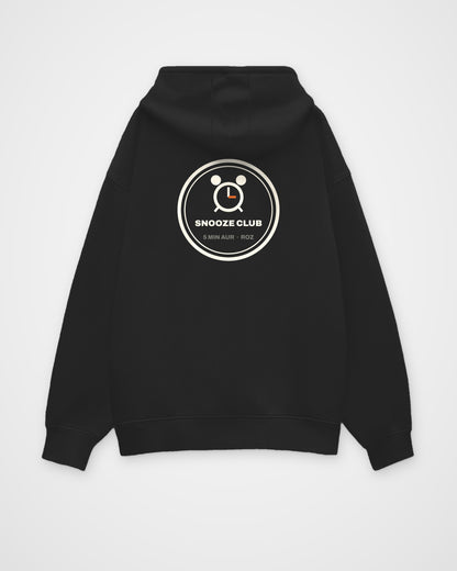 Black oversized hoodie, back view, a round SNOOZE CLUB badge with an alarm clock and 5 MIN AUR ROZ – digital mockup