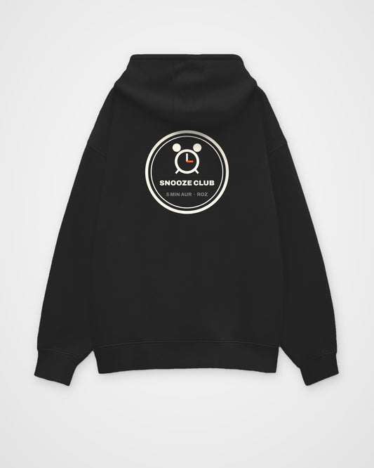 Black oversized hoodie, back view, a round SNOOZE CLUB badge with an alarm clock and 5 MIN AUR ROZ – digital mockup