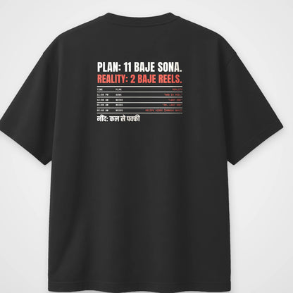 Black oversized t-shirt, back view, with a timetable reading Plan 11 baje sona, Reality 2 baje reels